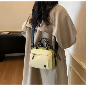 Detailed view of the lightweight cream and green crossbody bag on a model