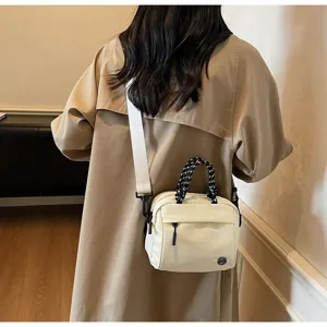 Detailed view of off-white crossbody bag with braided rope handle and wide strap