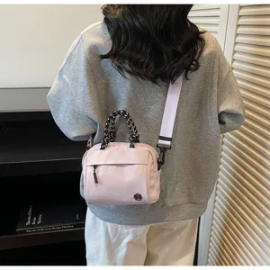 Back view of pink nylon crossbody bag with purple strap on gray sweatshirt