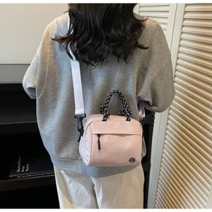 A detailed back view of a stylish pink crossbody bag featuring a woven rope handle