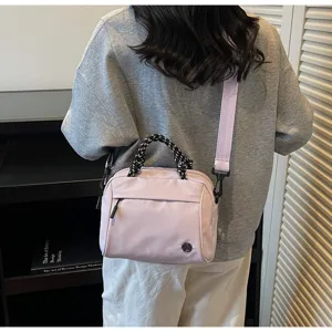 Detail view of a lightweight lavender crossbody bag with woven handles on a model.