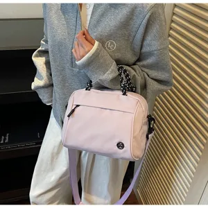 Detailed view of a light purple crossbody bag styled with a grey casual sweatshirt