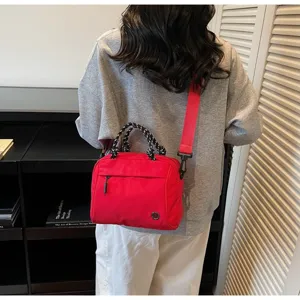 Stylish red lightweight crossbody handbag with braided handles shown in detail