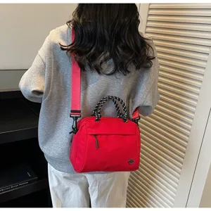 Detailed view of a woman carrying a stylish red crossbody bag with patterned handles