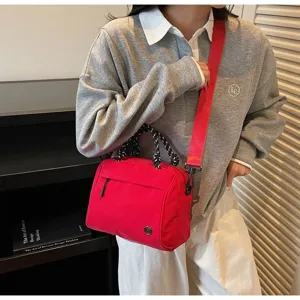 Red minimalist lightweight crossbody bag shown on a model in a casual indoor setting
