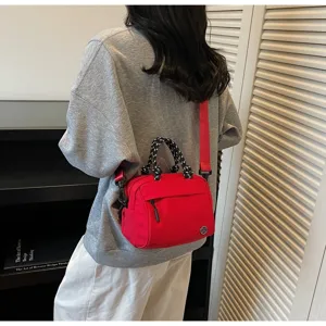 Modern red lightweight canvas crossbody bag worn by a model in a stylish home setting