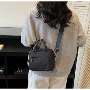Detailed back view of a woman wearing a black nylon crossbody bag with rope handle