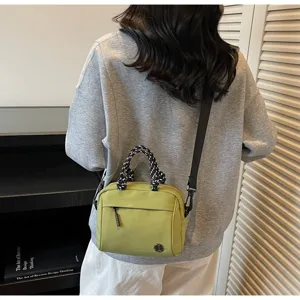 Detail view of a lightweight lime green crossbody square bag with braided handles