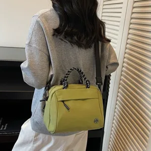 Stylish olive green nylon crossbody bag with braided handle shown on a model back view