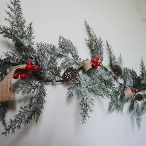 Detailansicht der verschneiten Weihnachtsgirlande mit roten Beeren und natürlichen Zapfen