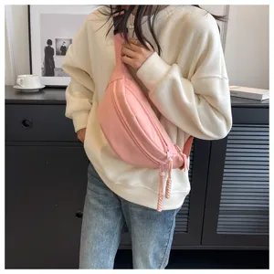 Stylish pink crossbody fanny pack with wide strap worn by model in a casual indoor setting