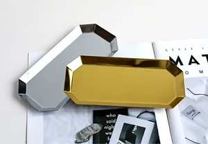 Nahaufnahme von goldenen und silbernen achteckigen Edelstahltabletts für Schmuck auf Magazin
