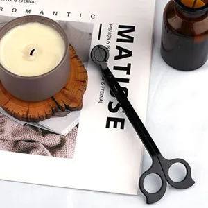 Coupe-mèche de bougie en acier noir avec poignée papillon sur fond de décoration