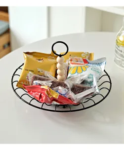 Detail van een Scandinavische zwarte metalen snackmand met een decoratieve houten kralenhandgreep