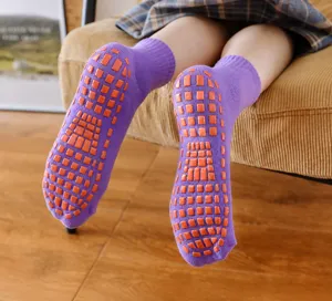 Nahaufnahme der lila rutschfesten Baumwollsocken mit orangen Gummipunkten an Sohle