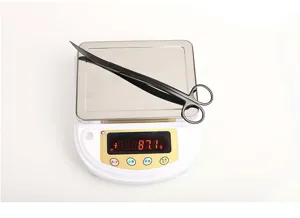 Close-up detail showing the weight of black stainless steel curved aquatic scissors on a scale