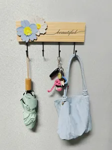Creative wooden wall hook with floral design and four black metal hangers in use