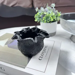 Detailed view of irregular black resin candle cup with organic rock-like texture