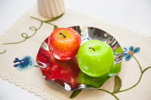 Gros plan d'une assiette à fruits ondulée en acier inoxydable avec des pommes décoratives.
