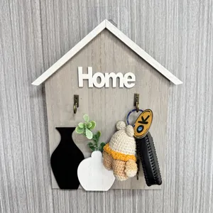 Close-up detail of a wooden house-shaped key holder featuring a Home sign and floral motifs