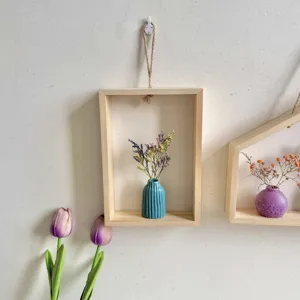 Minimalistische houten wandlijst in INS-stijl met blauwe vaas en droogbloemen