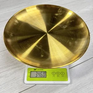 Nahaufnahme eines goldenen Edelstahltellers, der 346 g auf einer Waage wiegt, Metalldetail