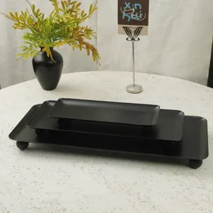 Macro view of matte black rectangular storage trays with decorative ball feet set of three