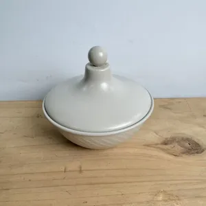 Arab style grey ceramic candy bowl with lid and ball finial on a rustic wooden surface