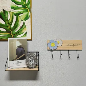 Detailed view of solid wood wall mounted coat hook with floral decor and black metal hooks.