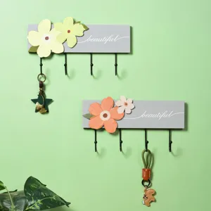 Detail view of minimalist floral wall hooks with 'beautiful' script on light green wall backdrop