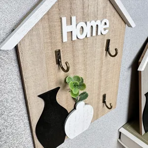 Close-up view of a wooden house-shaped key hook with decorative 3D Home letters and vase.