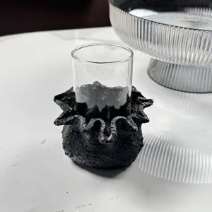 Close-up of the rough-textured black resin base of a modern decorative candle holder.