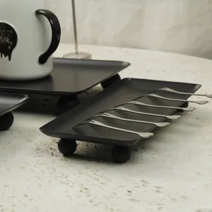 Detailed view of a modern black rectangular tray with ball feet for elegant dessert display