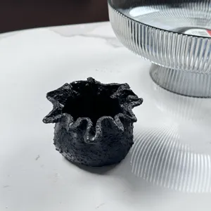 Detailed view of black textured resin candle holder with unique irregular wavy rim design