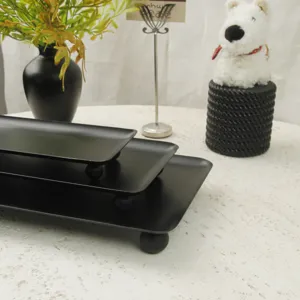 Detailed view of three matte black rectangular trays with minimalist spherical legs