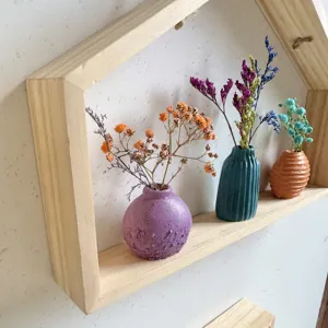 Mini getextureerde vazen met droogbloemen op een houten plank voor muurdecoratie