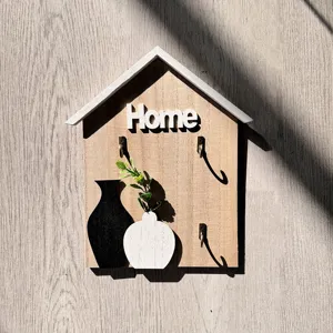 Detail of a decorative wooden house-shaped wall key hook with Home text and vase design