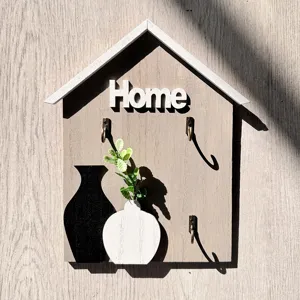 Detailed view of wooden house-shaped wall key holder with Home lettering and hooks.