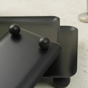 Macro shot of minimalist matte black rectangular storage tray with spherical ball feet