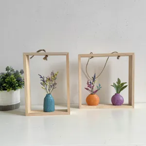 Detail van houten wandframes in INS-stijl met gekleurde minivazen en droogbloemen