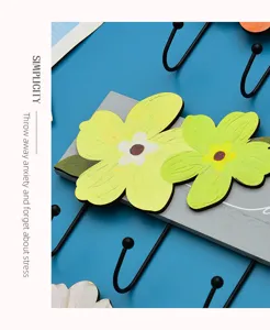 Close-up detail of a creative wooden flower wall hook with black metal hangers.