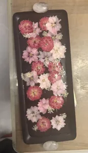 Detail view of a rectangular resin tray with elegant pink dried flowers and stone handles.