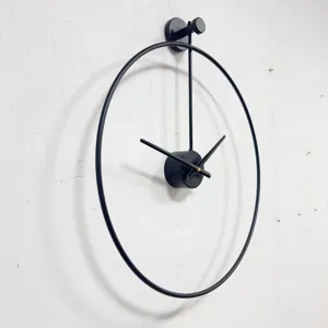Vista lateral de un reloj de pared minimalista de metal negro en una pared blanca