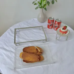 Detalle macro de una bandeja de acrílico transparente para postres con patas metálicas