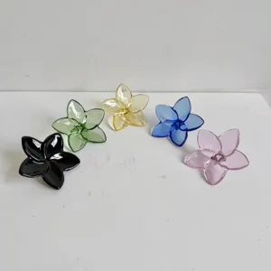 Detailed macro view of five colorful crystal glass plumeria flower ornaments on white background.