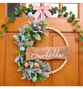 Detailed view of an artificial Easter wreath with rabbit ear leaves and hello wooden plaque