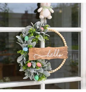 Detailed shot of an Easter wreath with plush bunny, eggs, and wooden hello sign
