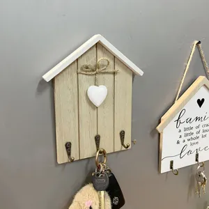 Detail eines hölzernen Schlüsselhalters in Hausform mit Vintage-Metallhaken und Herz