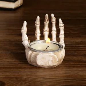 Halloween skeleton hand resin candle holder with a lit tealight on a wooden table