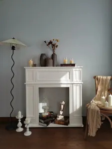 Manteau de cheminée décoratif français en bois blanc dans un cadre de salon chaleureux.